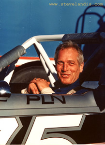 Paul Newman in race car smiling with blue background
